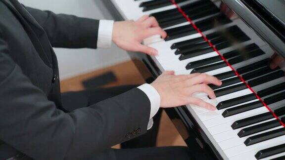 合上弹奏三角钢琴的钢琴家的手指最喜欢的古典音乐快乐和乐趣身着正式优雅套装的音乐家教育、练习、放松的理念