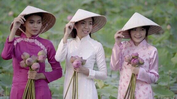 一名身穿越南民族服饰或奥代文化传统的年轻女子站在一艘小船上在莲花园里越南