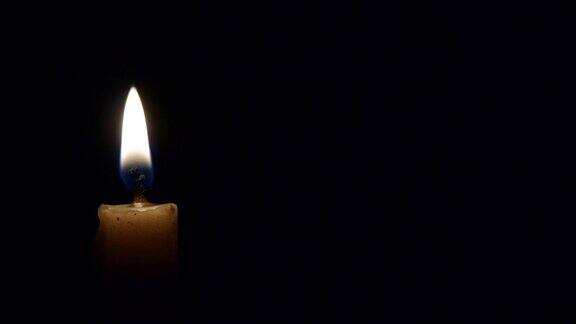 一支点燃的蜡烛在黑色的背景中明亮地燃烧着