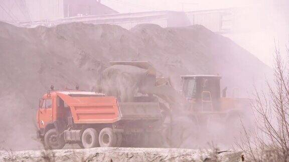 挖土机在采石场向自卸卡车装载沙子