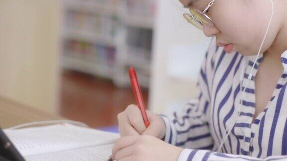 特写手亚洲女孩坐在图书馆看书