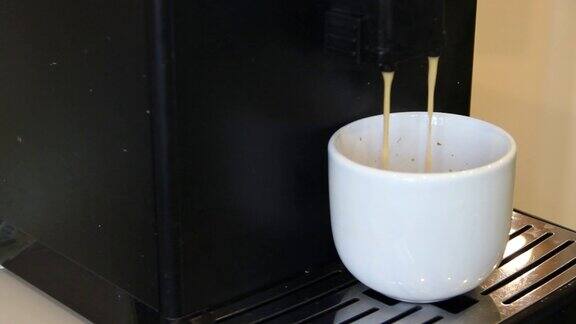 把咖啡机里的咖啡倒进一个白色的杯子里庆祝国际咖啡日