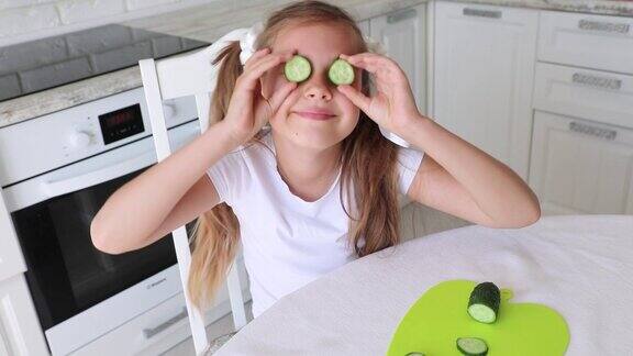 孩子在厨房吃健康食品维生素素食主义纯素食主义孩子把黄瓜杯放在眼前