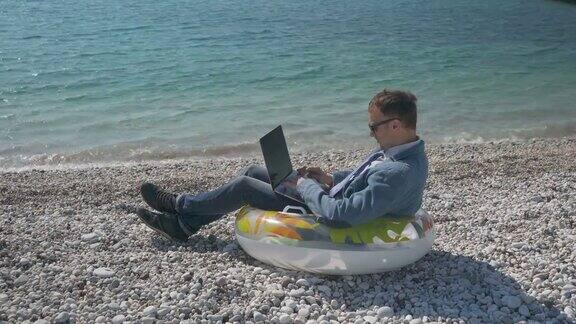 自由商人在海滩上用笔记本电脑远程工作