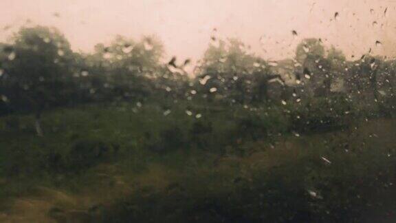 透过火车车厢的湿玻璃拍摄乡村景色窗外的雨和玻璃上的水滴