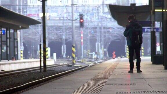 年轻的男游客背着背包在站台上等火车旅行