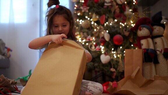 可爱的孩子在圣诞树下惊喜地收到礼物