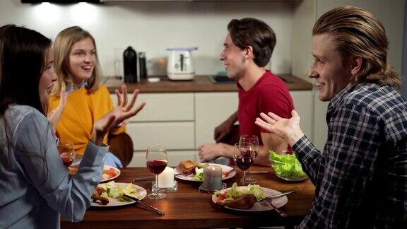 缩小镜头四个快乐的朋友两对夫妇一起在家里吃饭年轻人边吃边喝边谈笑风生