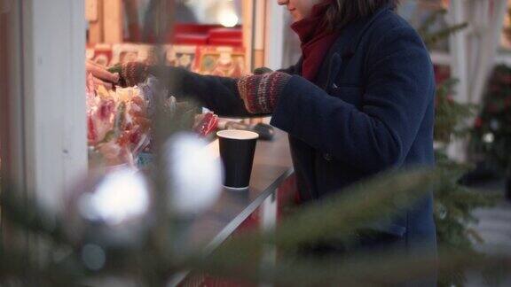 快乐的少女在圣诞市场买茶和糖果