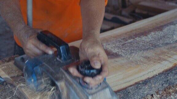 一个木匠在工厂里打磨一块大木板