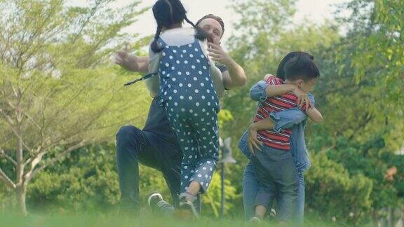 快乐的家庭在公园里孩子们在公园里跑着拥抱他们可爱的爸爸妈妈