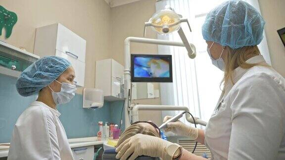 医生使用特殊的口腔内检查数码微型相机对牙齿进行检查在监视器上牙医和病人可以看到牙齿、牙齿问题的视频牙医在现代牙科诊所里治疗病人