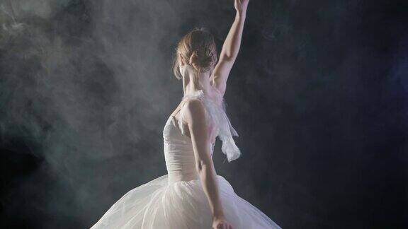 (中景)一个美丽的年轻芭蕾舞演员在聚光灯下优雅地旋转她穿着白色轻盈的现代芭蕾舞裙