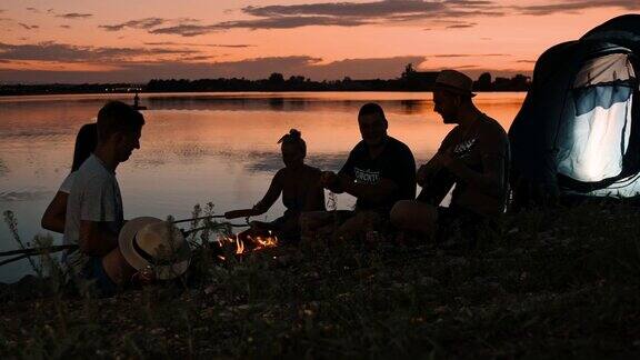 黄昏时分在湖边露营的一群年轻人