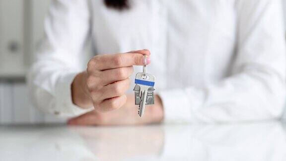 房产经纪人拿着房子的钥匙放在房子形状的钥匙链上