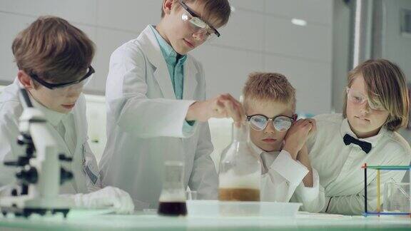 好奇的男孩在做科学实验实验室内部沸腾的泡沫液体