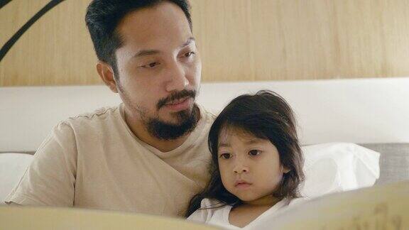 爸爸和小女孩在床上读故事书