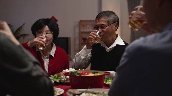 年夜饭的时候老夫妇的爷爷和奶奶在给家人敬酒庆祝春节