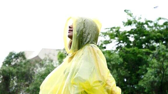 穿着黄色雨衣的年轻美丽幸福的女人享受着雨