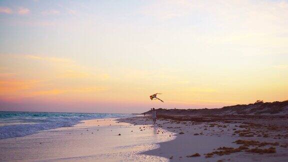 小女孩跑着放风筝在热带海滩上日落孩子们在海边玩耍有沙滩玩具的孩子