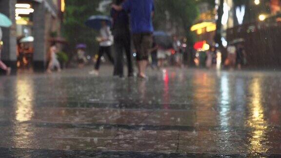 在大城市的商业街上人们打着伞走在雨中