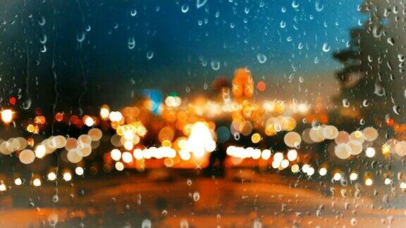 雨点落在玻璃窗上映衬着城市背景的绚丽多彩的散景灯光效果