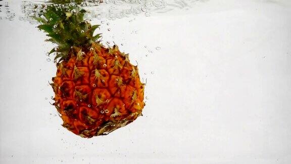 菠萝带着泡泡落在水中菠萝的视频在孤立的白色背景慢动作