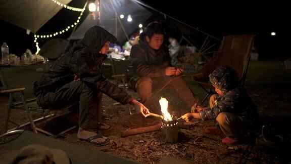 亚洲家庭在露营时坐在篝火旁