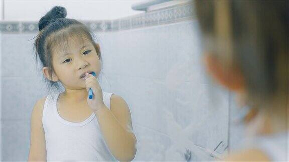 一个亚洲小女孩在浴室里刷牙