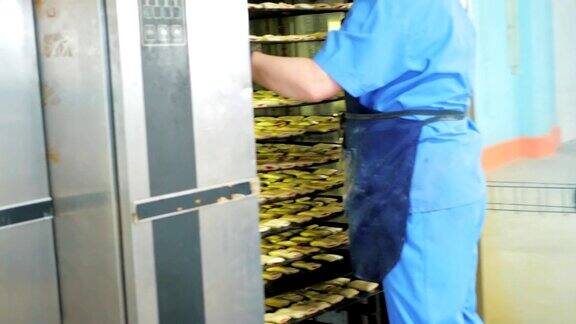 糖果工厂制造面包房工人将饼干放入工业烤箱