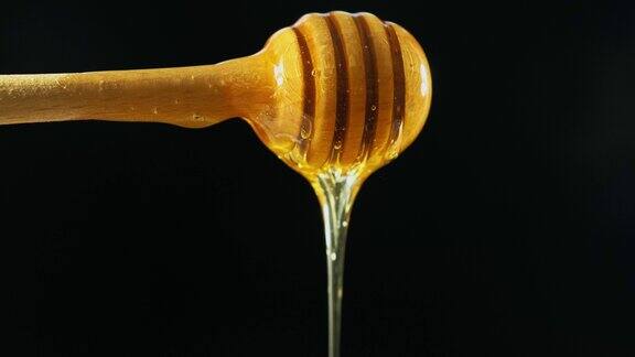 新鲜的蜂蜜从一个木头勺子流下来孤立在一个黑色的背景有机产品特写