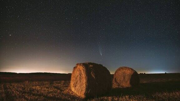 彗星NeowiseC2020F3在夜晚星空在夏季农业领域的草垛上夜晚的星星与收获后的干草捆的乡村景观农业FullHD间隔拍摄