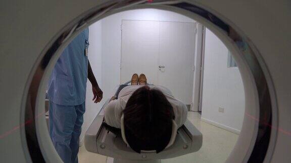 女病人躺下准备脑部扫描放射学家操作机器在医院