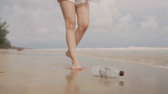 一个女人在海滩上捡塑料瓶