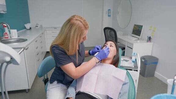 女牙医检查女病人并在牙科诊所规定治疗方法
