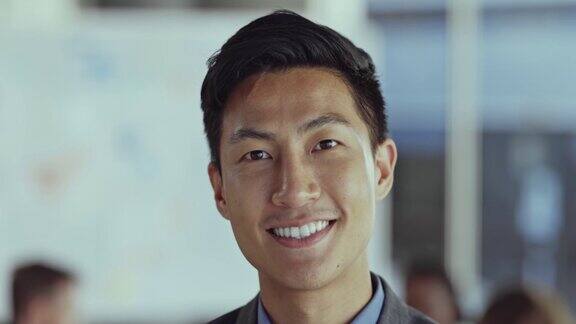 快乐的亚洲华人商人独自站在办公室里一个年轻的亚洲商人在办公室微笑的脸