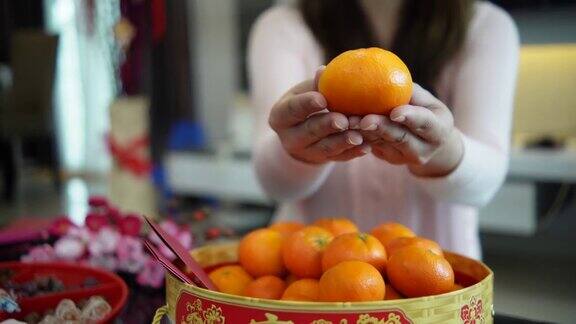 亚洲华人微笑的妇女手拿桔子在生活大厅在中国新年