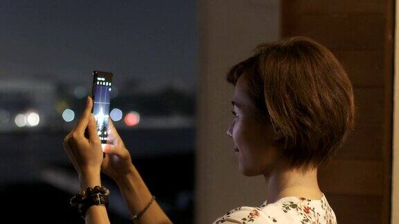 美丽的游客们用智能手机在湄南河上的黎明寺拍照