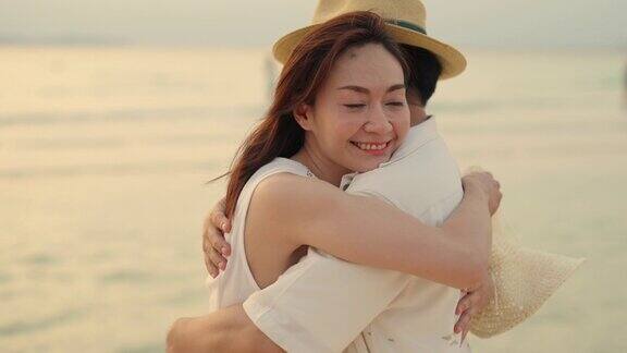 4K快乐的亚洲夫妇散步和拥抱对方而旅行在热带海滩在夏天的日落