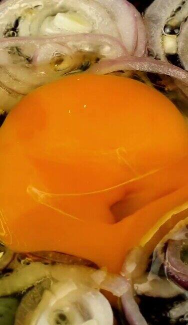 准备在煎锅里煎洋葱圈上有蛋黄的炒蛋