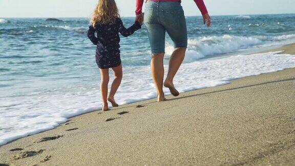 女人和女儿在海滩上散步的背影