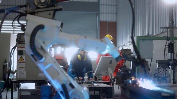 工程师配合男女技术员维修控制继电器机器人手臂系统焊接用平板电脑控制质量操作过程工作重工业4.0制造工厂