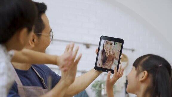 亚洲的父亲和孩子们在电子平板电脑上与妈妈进行视频通话