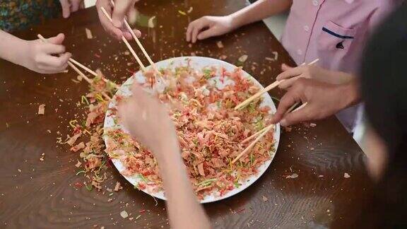 一个亚洲家庭在团圆饭上用传统食物“生鱼”庆祝中国新年