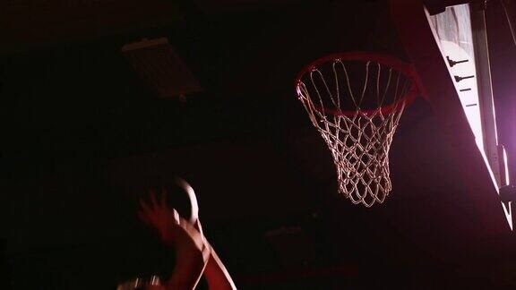 一个篮球运动员扣篮昏暗的灯光慢动作从下面看