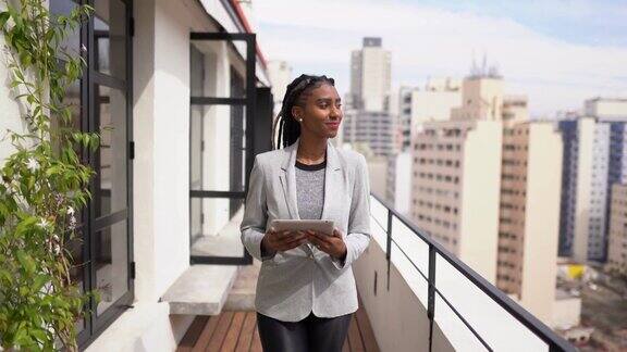 一名年轻女子在公寓的阳台上使用电子平板电脑时在思考