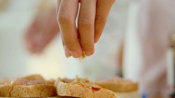 手把干肉丝撒在桌上自制的三明治上慢动作