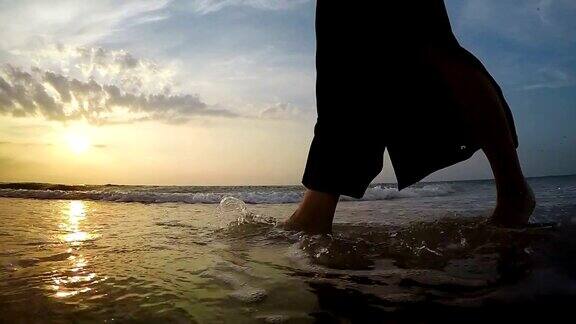 一个女人在日落时分走在沙滩上的慢镜头