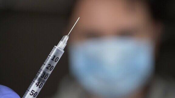 戴蓝手套的医生提供注射疫苗的注射器