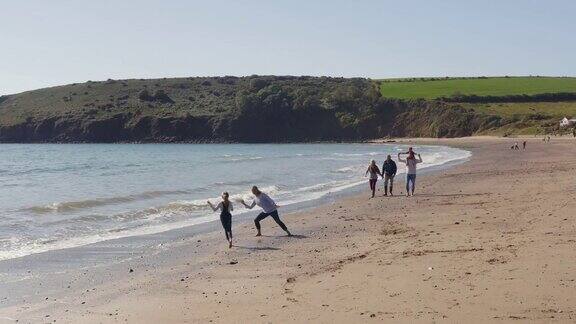无人机拍摄的多代家庭度假沿着海滩散步打破海浪